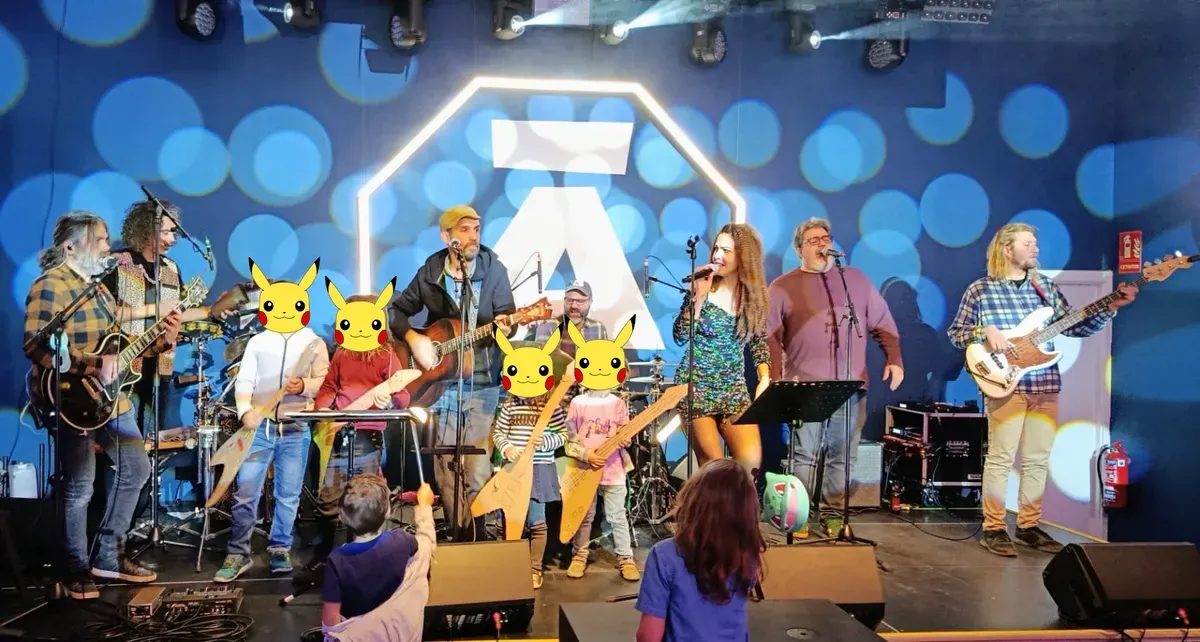 Músicos y niños con guitarras de cartón tocando juntos en el escenario en un evento de rock familiar